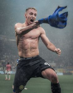 a shirtless soccer player is on the field with his mouth open and hands in the air