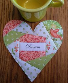 two heart shaped coasters sitting on top of a wooden table next to a cup