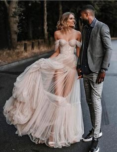 a man and woman standing next to each other in the street wearing wedding gowns