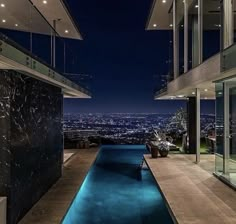 an indoor swimming pool in the middle of a house at night with city lights visible