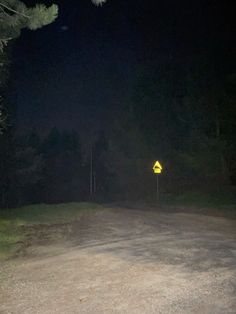 a yellow sign sitting on the side of a road in the middle of a forest