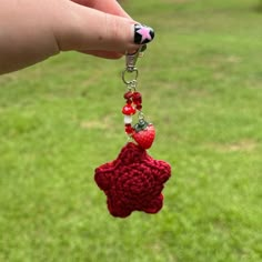 a hand holding a red crocheted star shaped keychain