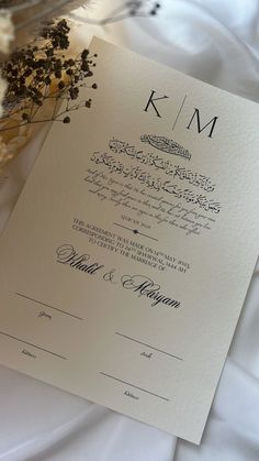 the wedding program is displayed on a white tablecloth with dried flowers in front of it