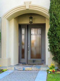 a couple of doors that are in front of a house with plants on the side