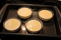 four glasses filled with liquid sitting on top of an oven tray in front of the stove