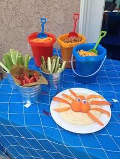 a blue table topped with plates and buckets filled with food