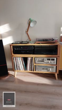 a wooden entertainment center with various records on it and a lamp next to the tv