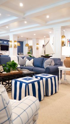 a living room with blue and white furniture in the center, along with striped ottomans