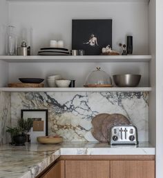 a kitchen with marble counter tops and wooden cabinets, including a toaster on the counter