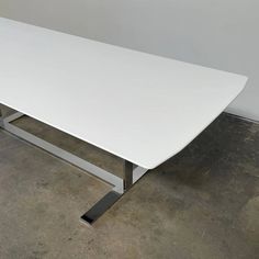 a white table sitting in the middle of a room with concrete flooring and walls