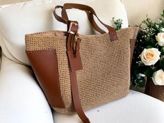 a brown purse sitting on top of a white chair next to flowers and vases