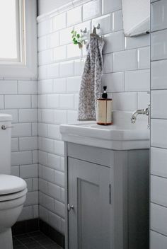 a white toilet sitting next to a sink in a bathroom under a window with a towel hanging on the wall