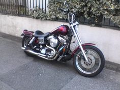 a motorcycle is parked on the side of the road next to a wall and fence