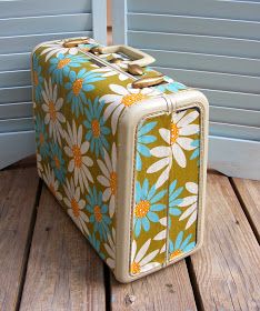 a suitcase sitting on top of a wooden floor next to a blue building with shutters