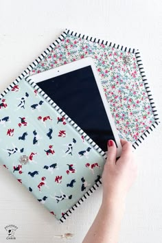 a person holding an ipad in front of two fabric squares on top of each other