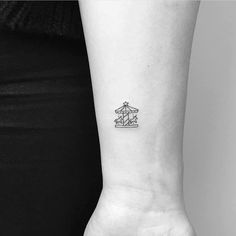 a black and white photo of a woman's arm with a small boat tattoo on it