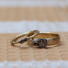 two gold wedding rings sitting on top of a table