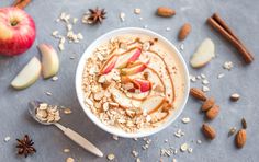 an oatmeal bowl with apples, nuts and cinnamon sticks on the side