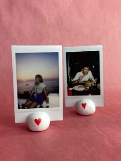 two polaroids with hearts on them sitting next to each other in front of a pink background