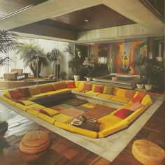 a living room filled with yellow couches and potted plants on top of it