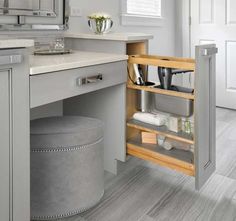 an open cabinet in the middle of a kitchen with gray cabinets and white counter tops