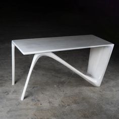 a white coffee table sitting on top of a cement floor next to a black wall