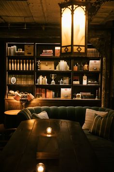 a dimly lit room with bookshelves and couches in the corner, along with candles