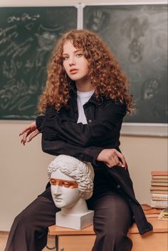 a woman sitting on top of a white busture in front of a chalkboard