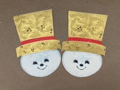 two blue and gold hats with faces painted on them, one has a smiling face