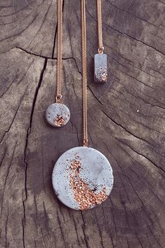 two necklaces with different designs on them sitting on a piece of wood