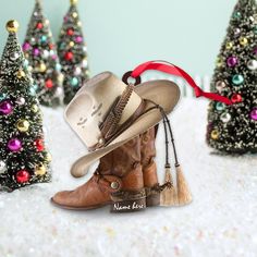 there is a cowboy hat and boots in front of small trees with ornaments on them