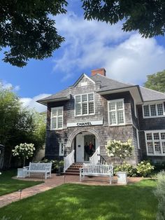 a large gray house with two white benches in front