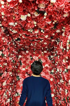 a person standing in front of a red flower wall