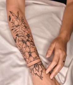 a woman with a flower tattoo on her arm and wrist is laying down in bed