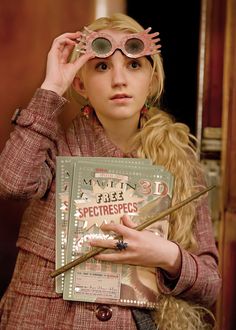 a woman with long hair and glasses holding a book in front of her eyeglasses