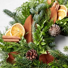 an evergreen wreath with oranges, cinnamon and pine cones