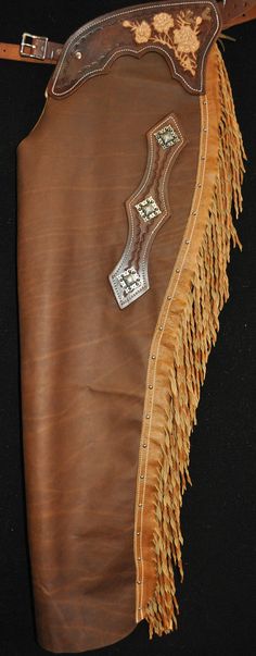 a brown leather purse with fringes on the bottom and side, sitting on a black surface