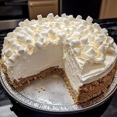 a cake with white frosting and marshmallows is on a silver platter