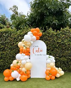 an orange and white balloon arch with the words'a little cake is on the way '