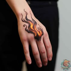 a woman's hand with a tattoo on it that has flames coming out of it