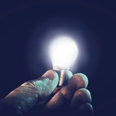 a person holding a light bulb in their hand with the light shining brightly on them