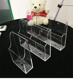 a teddy bear sitting on top of a table next to some clear acrylic boxes