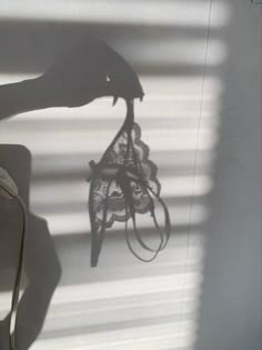 the shadow of a person's hand holding an object in front of a window