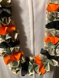 an origami wreath made out of dollar bills and orange ribbon tied around it