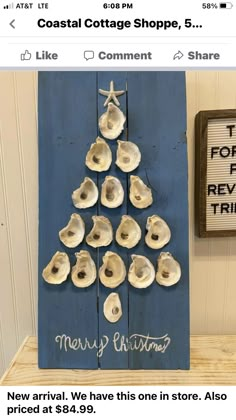 a christmas tree made out of seashells is displayed on a wooden shelf next to a sign that says coastal cottage shoppe, 5