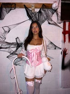 a woman dressed up as a zombie holding a white teddy bear and a pink umbrella