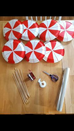 several red and white paper plates sitting on top of a wooden table next to scissors