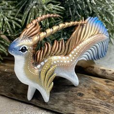 a decorative figurine is sitting on a piece of wood next to a christmas tree