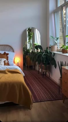 a bed sitting next to a window in a room with wooden floors and white walls