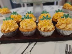 several cupcakes with yellow frosting and green leaves on top are sitting on a table